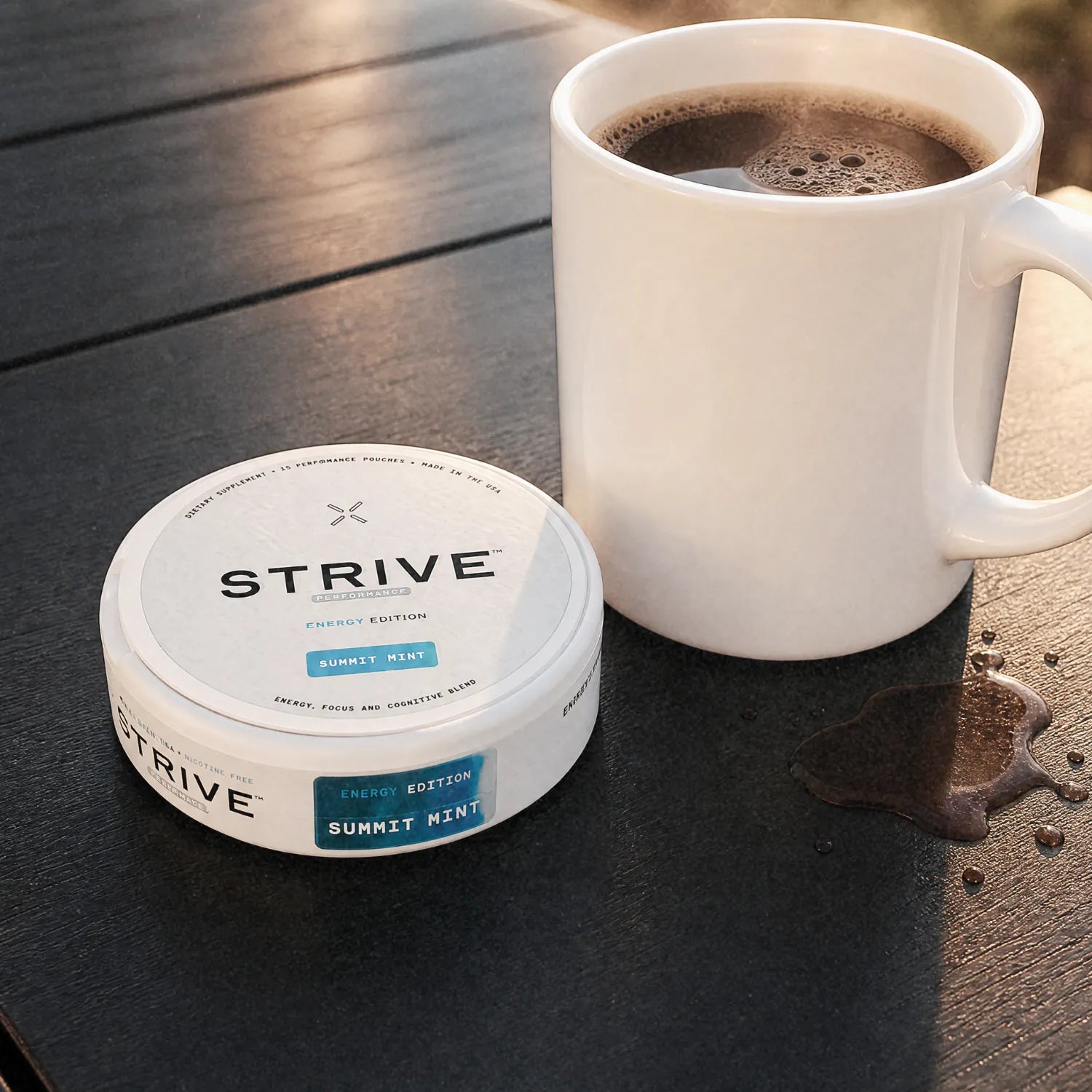A Strive can on a dark wooden table beside a mug of black coffee