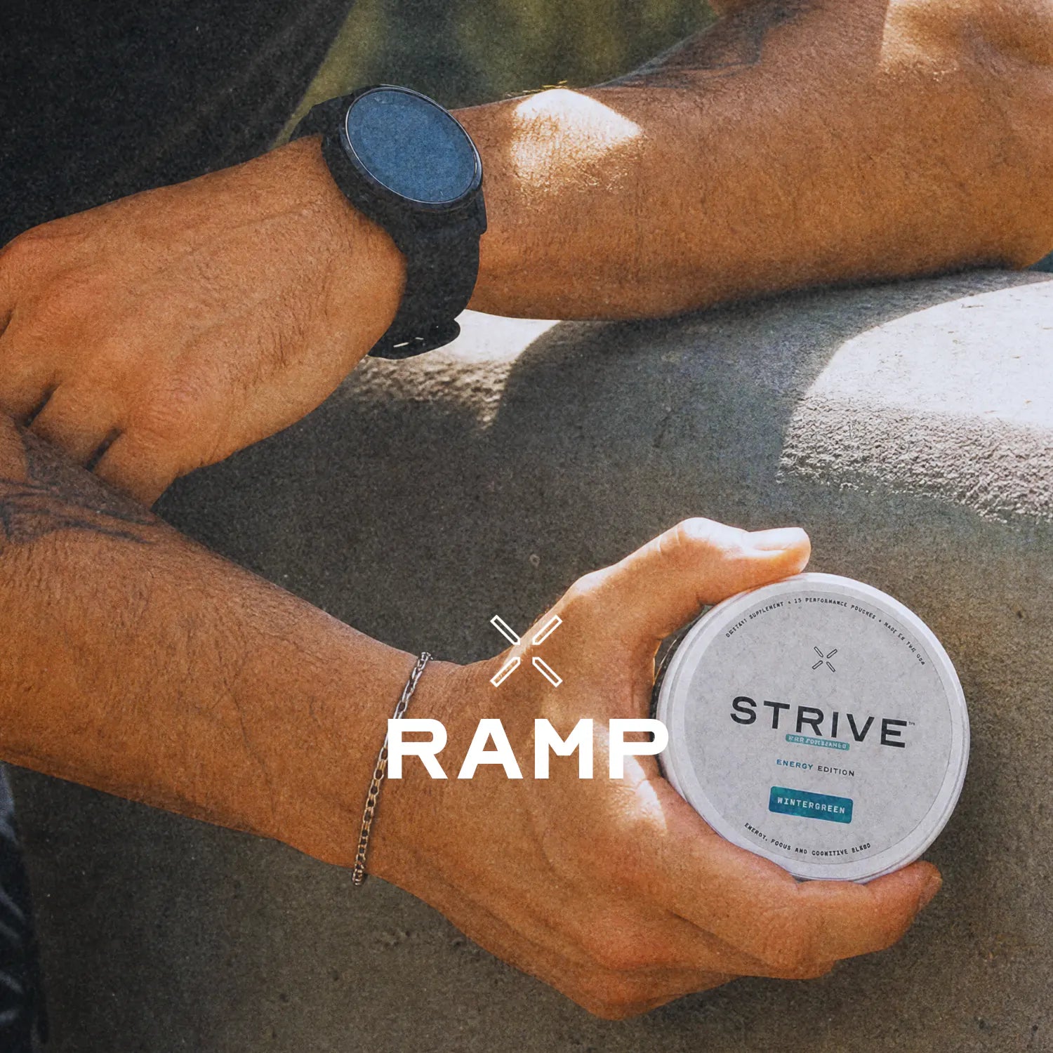 Forearms resting on a knee outdoors, an open Wintergreen tin held in one hand